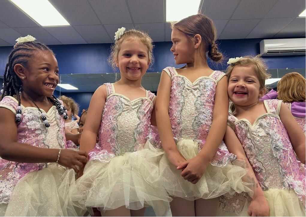 Young Kinetic Dance Force dancers smiling in their recital costumes