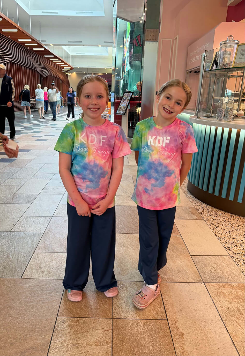 Two smiling young Kinetic Dance Force dancers in their KDF Dance Troupe shirts
